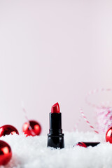 Red lipstick in the snow on a pink background. Christmas gifts for women. New Year's Eve, festive...