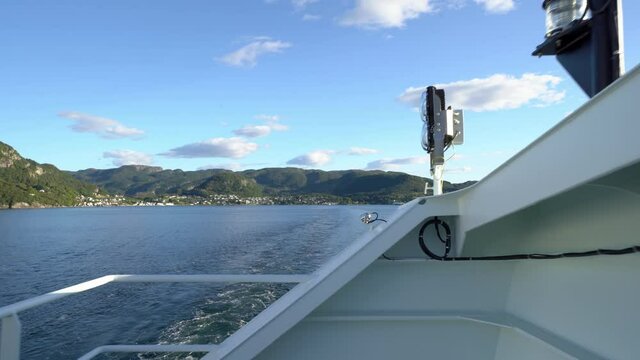 Passengers view from Hydrogen powered ferry Hydra - Walking against fence and looking astern with Hjelmeland in background - Ferry crossing to Nesvik during sunny summer day - Norway