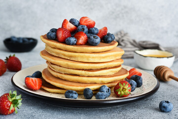 Stack of pancakes with berries and honey.on a concrete background.