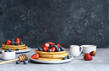 Homemade pancakes with strawberries and blueberries for breakfast on the kitchen table.