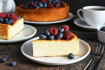 Cheesecake new york. Slice cheesecake with raspberries and blueberries, a cup of tea on a dark background.