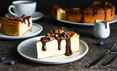 Cheesecake new york. Slice cheesecake with chocolate sauce and a cup of coffee on a dark concrete...
