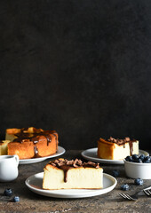 Cheesecake new york. Slice cheesecake with chocolate sauce and a cup of coffee on a dark concrete background.