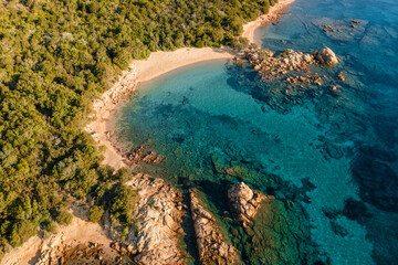 View from above, stunning aerial view of a green coastline with some beaches bathed by a turquoise sea during a beautiful sunrise. Liscia Ruja, Costa Smeralda, Sardinia, Italy.