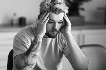 Black and white portrait of depressed young man at home