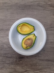 Top view of ripe avocado (Persea americana) on white plate 