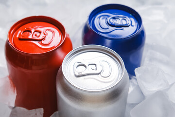 Cans of soda on ice cubes, closeup