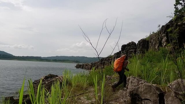 WONOSOBO, INDONESIA - Aug 05, 2021: An HD footage of a man walking on a rocky riverbank