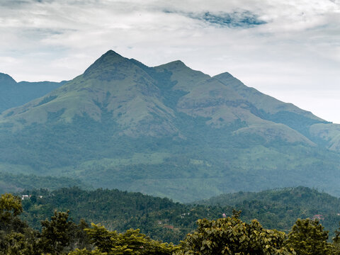 Landscape oriented wallpaper poster background of highest mountain in wayanad Chembra peak hills on a hazy day in Meppadi.