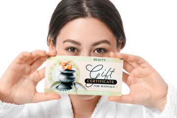 Young Asian woman with gift certificate for massage on white background