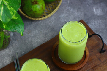 Jus Alpukat or Avocado juice served with clear glass and cut of avocado fruits. 