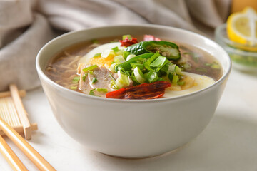Tasty Chinese soup with chicken in bowl on light background, closeup