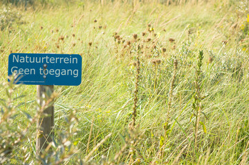 Dutch blue no access sign, with nature in the background. Translation: Natural site no access
