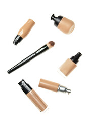 Bottles of cosmetic tonal foundations and makeup brush on white background