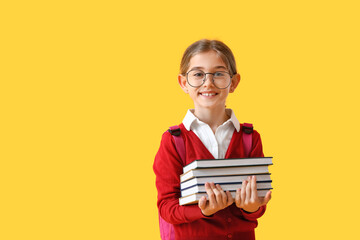 Cute little school girl with books on color background