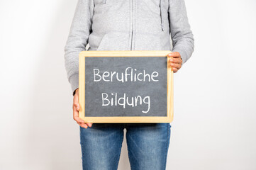 Eine Frau hält eine Tafel auf der Berufliche Bildung steht