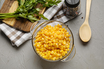 Bowl with corn kernels and spices on grey background