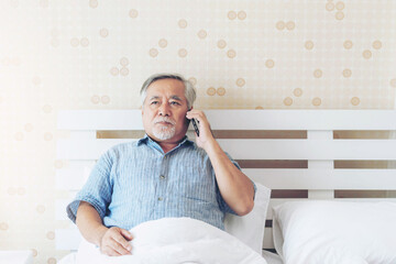 Fototapeta premium Senior Asian man , retired , old man make a call mobile phone on a bed in the bedroom , He was stressed , serious and worried - lifestyle senior at home concept