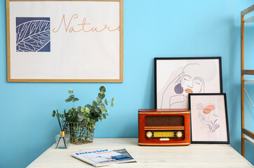 Table with retro radio receiver and pictures near color wall