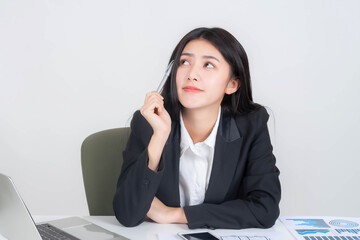 Portrait of Asian business young woman company employee working in front of a laptop computer on office desk , thinking about how to make money online from the money- lifestyle business people concept