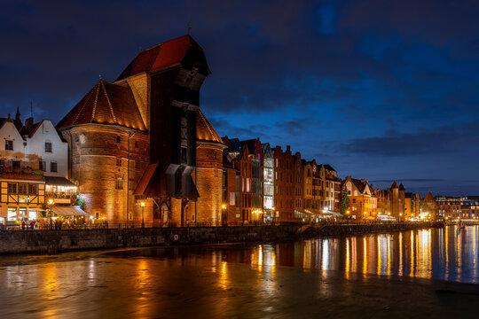 Gdask Old Town - the crane gate and houses on the Motawa River in the evening time - the light reflects in the water