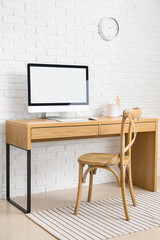 Modern workplace with computer near brick wall