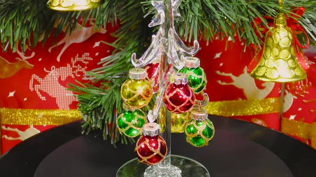 Video card with the approach of a small decorated Christmas tree rotates on the background of a green Christmas tree and gifts
