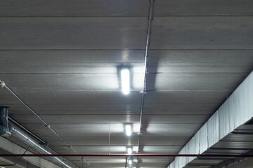 Ceiling of a garage with fluorescent tube lamps. White light in the parking lot of a shopping...