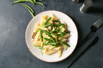 Plate of tasty pasta with vegetables on dark background