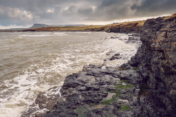 Rough coast line of Atlantic ocean, Rosses point, county Sligo, Ireland, Benbulben flat top mountain covered with snow in the background. Winter season. Irish nature landscape.