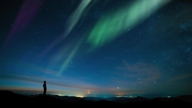 The man stand on mountain top on a beautiful polar light background. time lapse