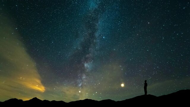 The man stand on mountain top on a beautiful night sky background. timelapse