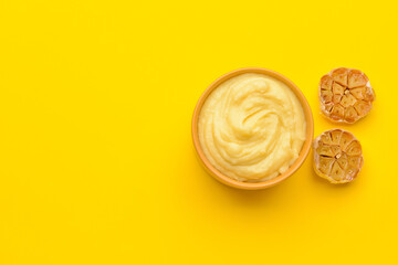 Bowl of tasty mashed potatoes with garlic on color background