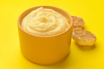 Bowl of tasty mashed potatoes with garlic on color background, closeup