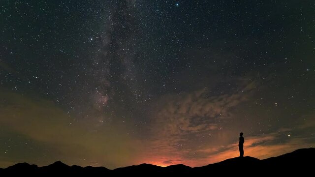 The man stand on mountain top on a beautiful night sky background. time lapse