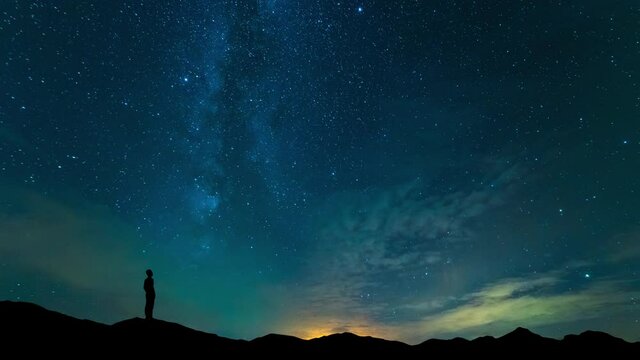 The man stand on mountain top on a starry sky background. time lapse