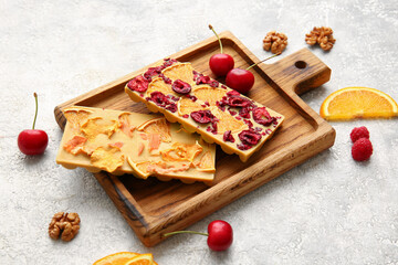 Handmade chocolate bars with fruits, berries and nuts on light background