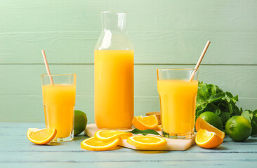 Jug and glasses of tasty orange juice on color wooden background