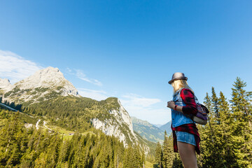 Fototapeta na wymiar woman enjoying beauty of nature looking at mountain. Adventure travel, Europe. Woman stands on background with Alps.