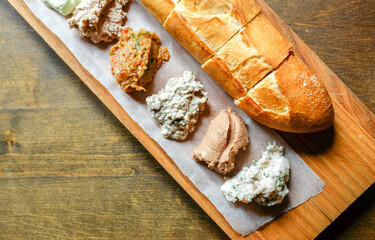 Various spreads on bread and fresh French baguette on a wooden table. Hearty breakfast. Blurred and selective focus.