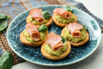 Tasty sandwiches with guacamole, ham and basil on table, closeup