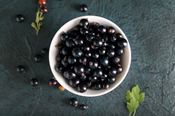 Bowl with ripe black currant on dark background