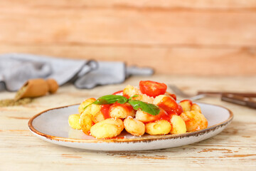 Delicious gnocchi with tomato sauce in plate on wooden table