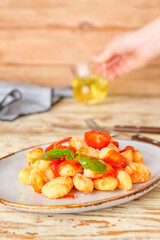 Delicious gnocchi with tomato sauce in plate on wooden table