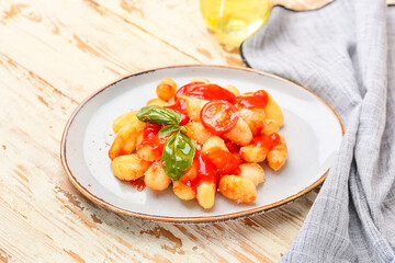Delicious gnocchi with tomato sauce in plate on wooden table
