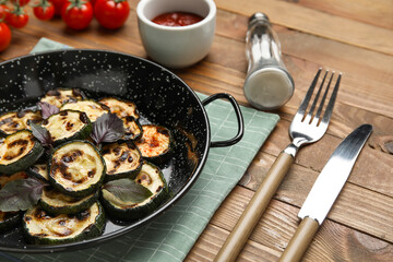 Frying pan with tasty grilled zucchini on wooden background, closeup