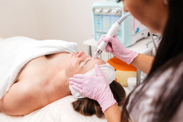Beauty salon. The cosmetologist makes a aqua peeling procedure for the client. View from the...