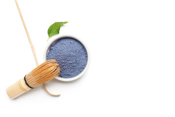 Bowl of powdered blue matcha tea, chasen and chashaku on white background
