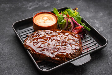 Grilled pork steak with sauce and vegetables in a skillet with place for text