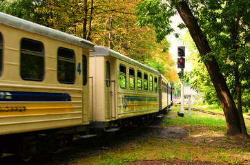 The children's train arrives at the station. Blurred motion. Scenic nature landscape in Syretsky Park. Kyiv Children's Railway after renovation. Blurred view of the coaches